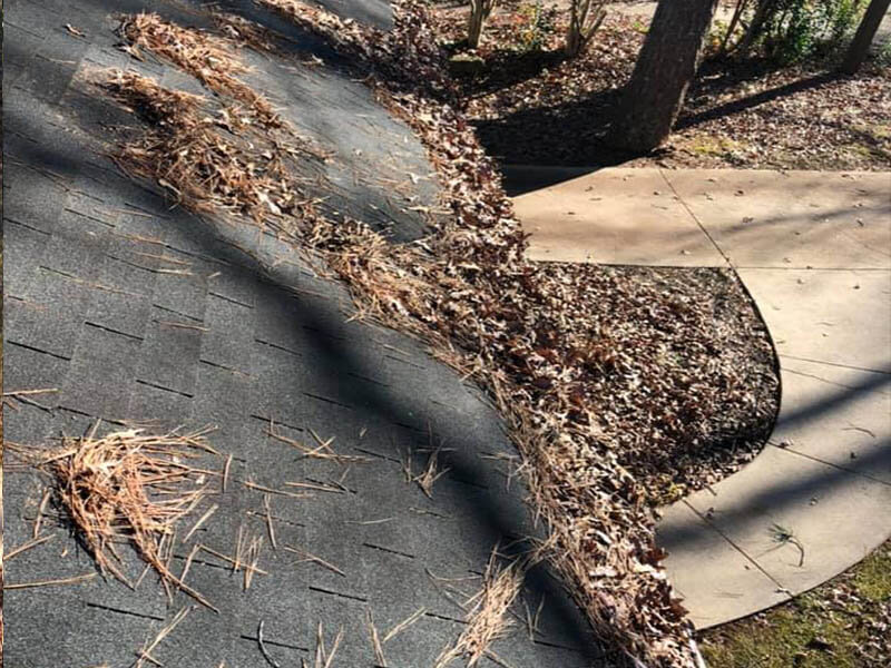 Roof gutter before cleaning — heavy debris and leaf buildup visible on Atlanta home